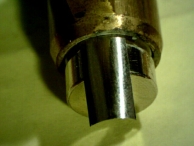 Photo of a shim, a thin metal strip, partially inserted into the back of a cylinder.
